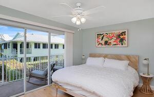 Main floor bedroom with balcony overlooking pool and canal