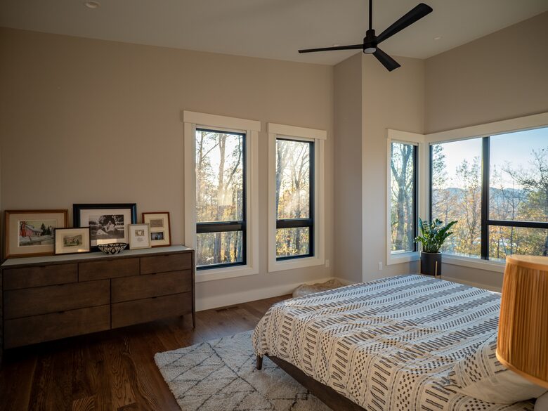 Master suite with king bed, surrounded by wooded views