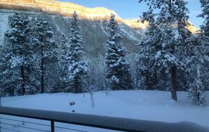 Deck with views of snow covered cliffs and trees.