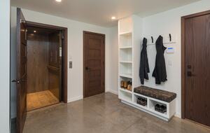 Bottom floor entryway with open elevator door and bench.
