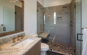 Master bathroom with two sinks, toilet, and walk-in shower.