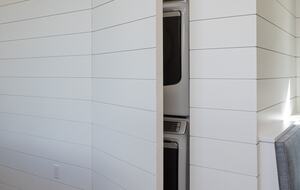 Stacked washer & dryer hidden behind shiplap wall doors.