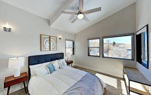 Master bedroom with slanted ceilings, windows & ceiling fan