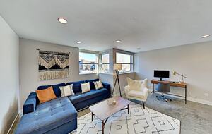 Bottom floor living room with blue sectional and office desk