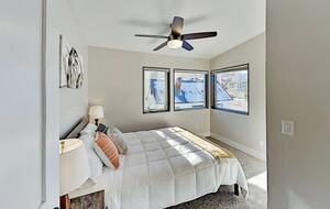 Guest room with queen bed, ceiling fan, and windows