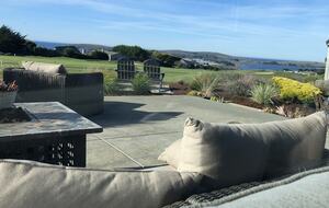 Looking outside from sofa to patio with lounge and firepit.