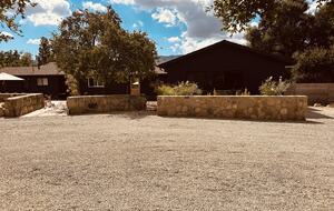 Black modern ranch-style with stone walls around front patio