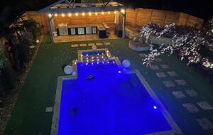 Night view from sunroom of pool deck and outdoor kitchen