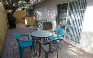 Private backyard with table, chairs, beach box and grill.
